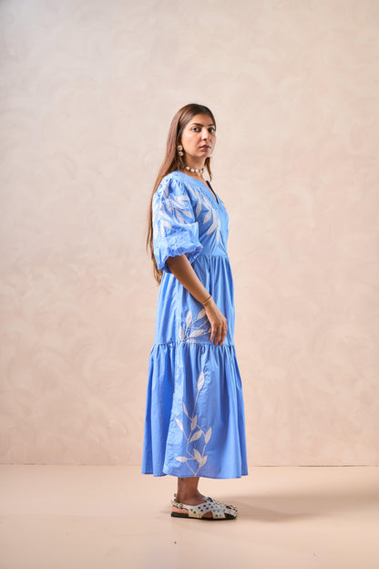 Woman wearing a blue dress with floral patterns against a beige background