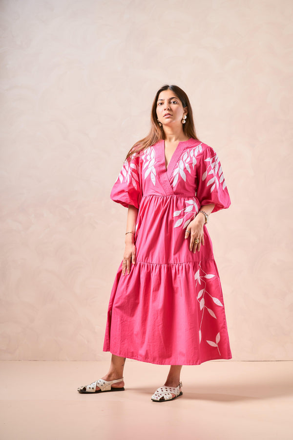 Woman wearing a pink dress with white floral patterns against a beige background