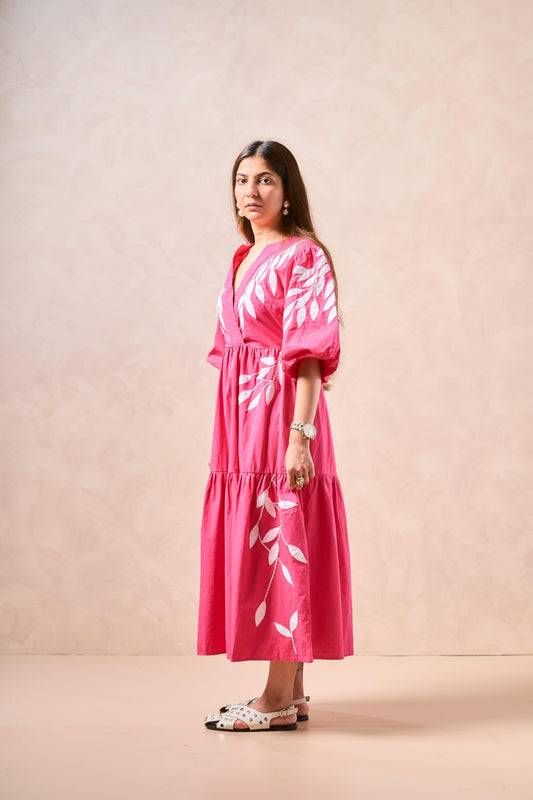 Woman wearing a pink dress with white floral patterns against a beige background