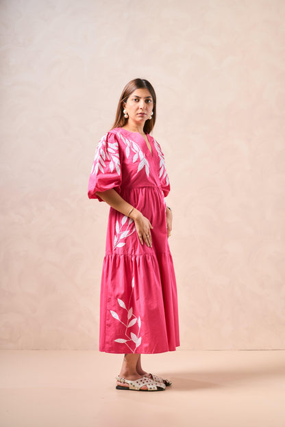 Woman wearing a pink dress with white floral patterns on a beige background