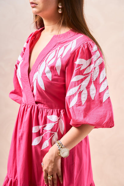 Woman wearing a pink dress with white leaf patterns on a beige background