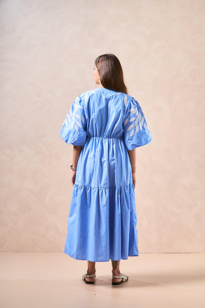 Woman wearing a blue dress with white patterns on a beige background