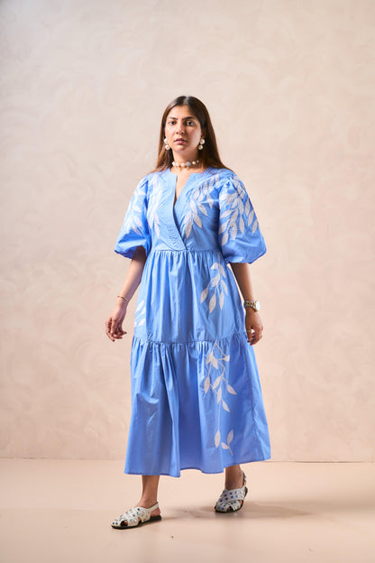 Woman wearing a blue dress with white patterns against a beige background