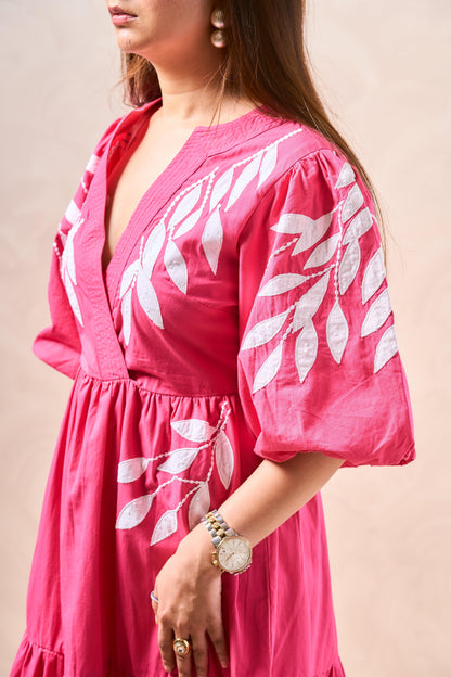 Woman wearing a pink dress with white leaf patterns on a beige background