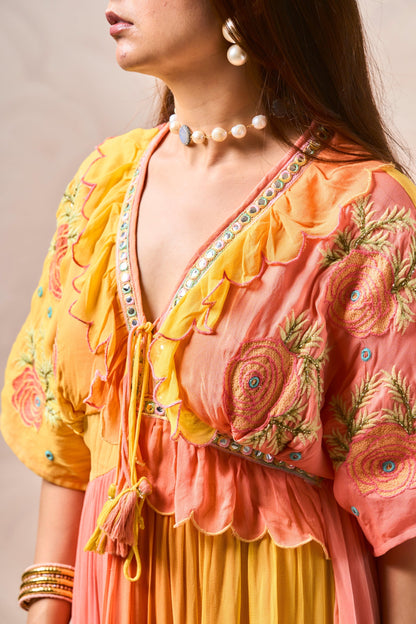 Woman wearing a traditional outfit with floral embroidery in pink and yellow.