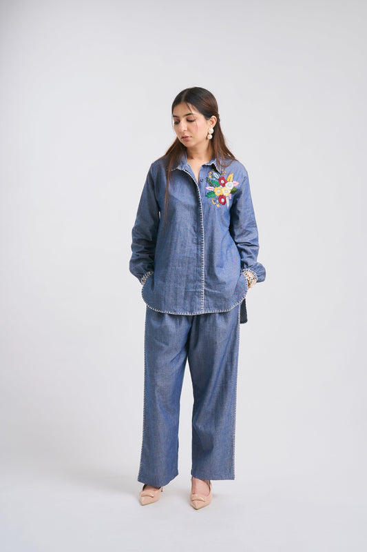 Woman wearing a denim outfit with floral embroidery on a white background
