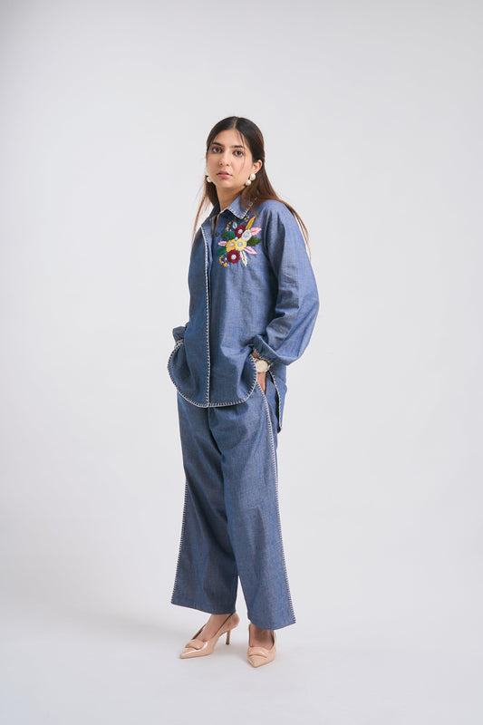 Woman wearing a blue outfit with floral embroidery on a white background