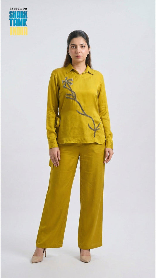 Woman wearing a mustard yellow outfit with floral design on a white background