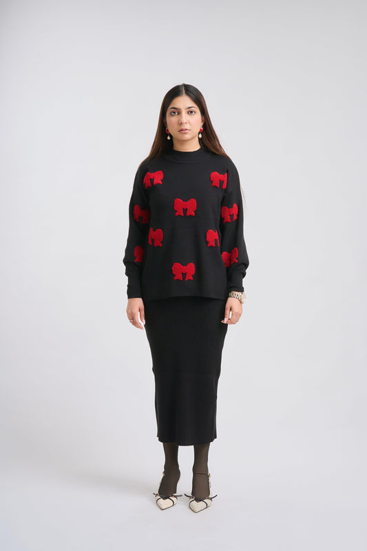 Woman wearing a black sweater with red bow patterns on a white background