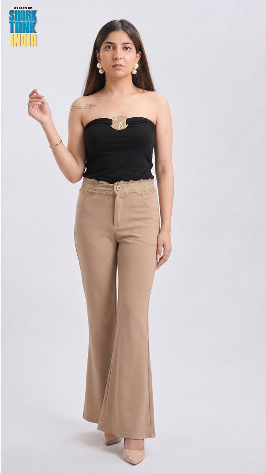 Woman wearing a black strapless top and beige high-waisted pants on a white background