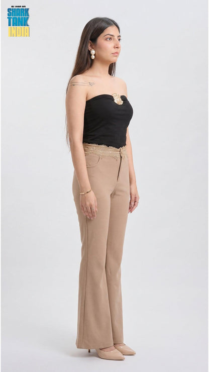 Woman wearing a black strapless top and beige pants on a white background