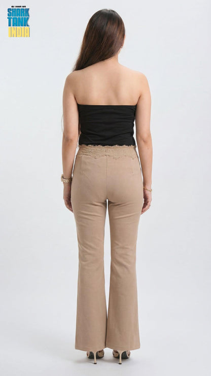 Woman wearing a black strapless top and beige flared pants on a white background