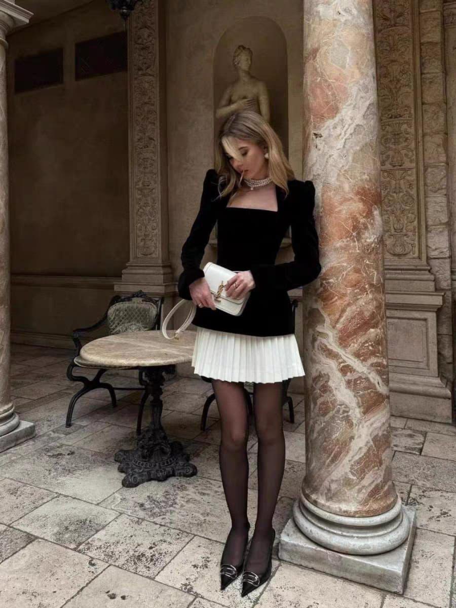 Woman in formal attire standing in an elegant outdoor setting with classical architecture.