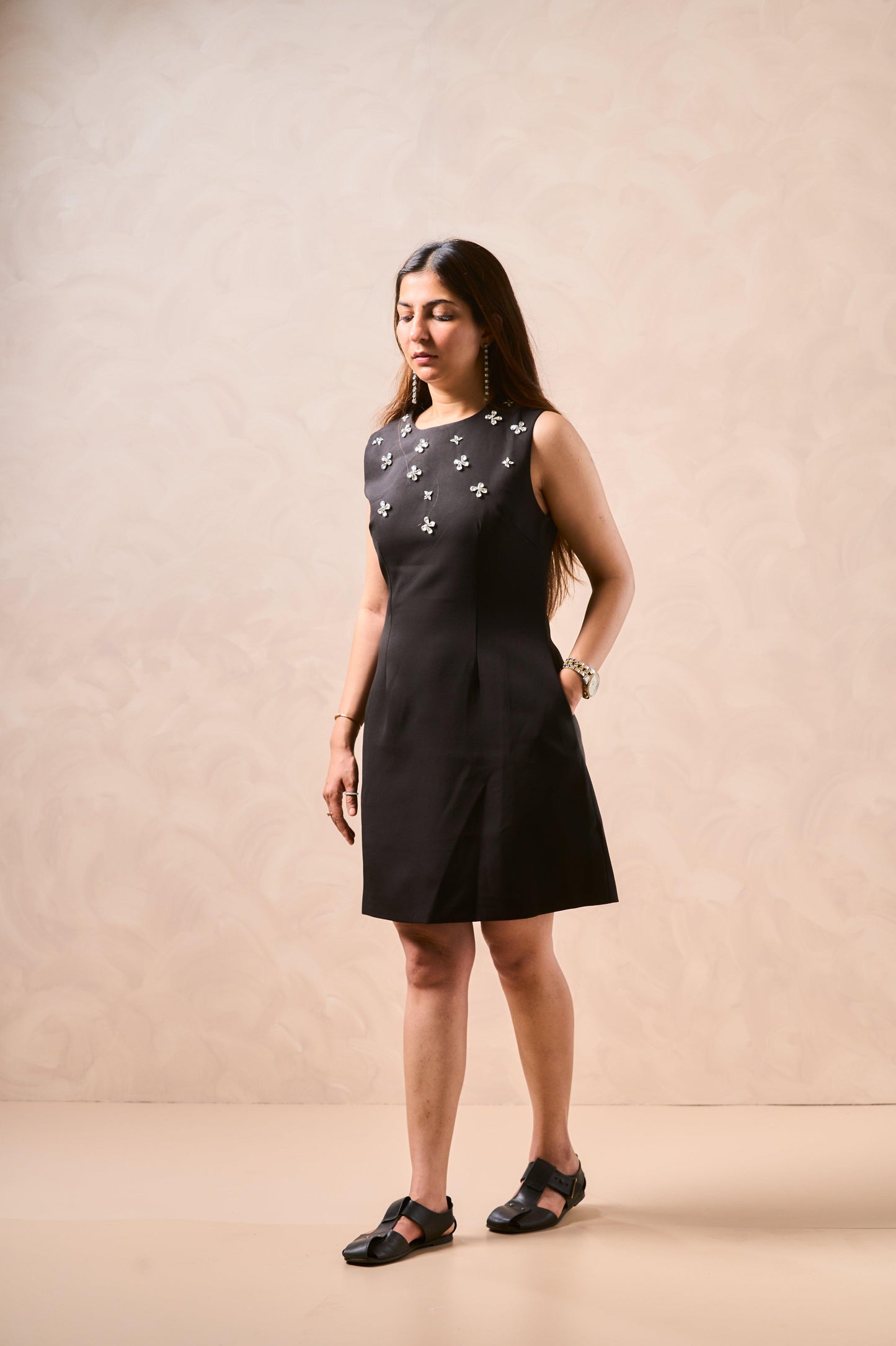 Woman wearing a black dress with star patterns against a beige background