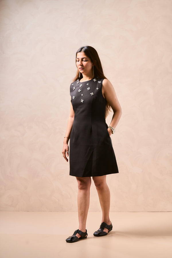 Woman wearing a black dress with star patterns against a beige background