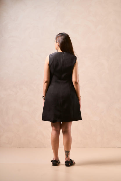 Person wearing a black sleeveless dress against a beige background