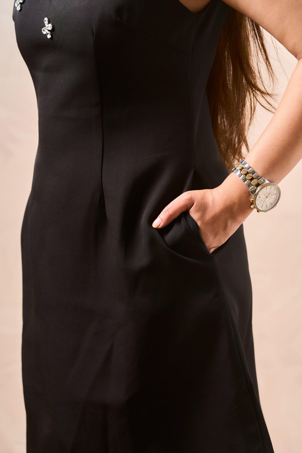 Person wearing a black dress with a beige background