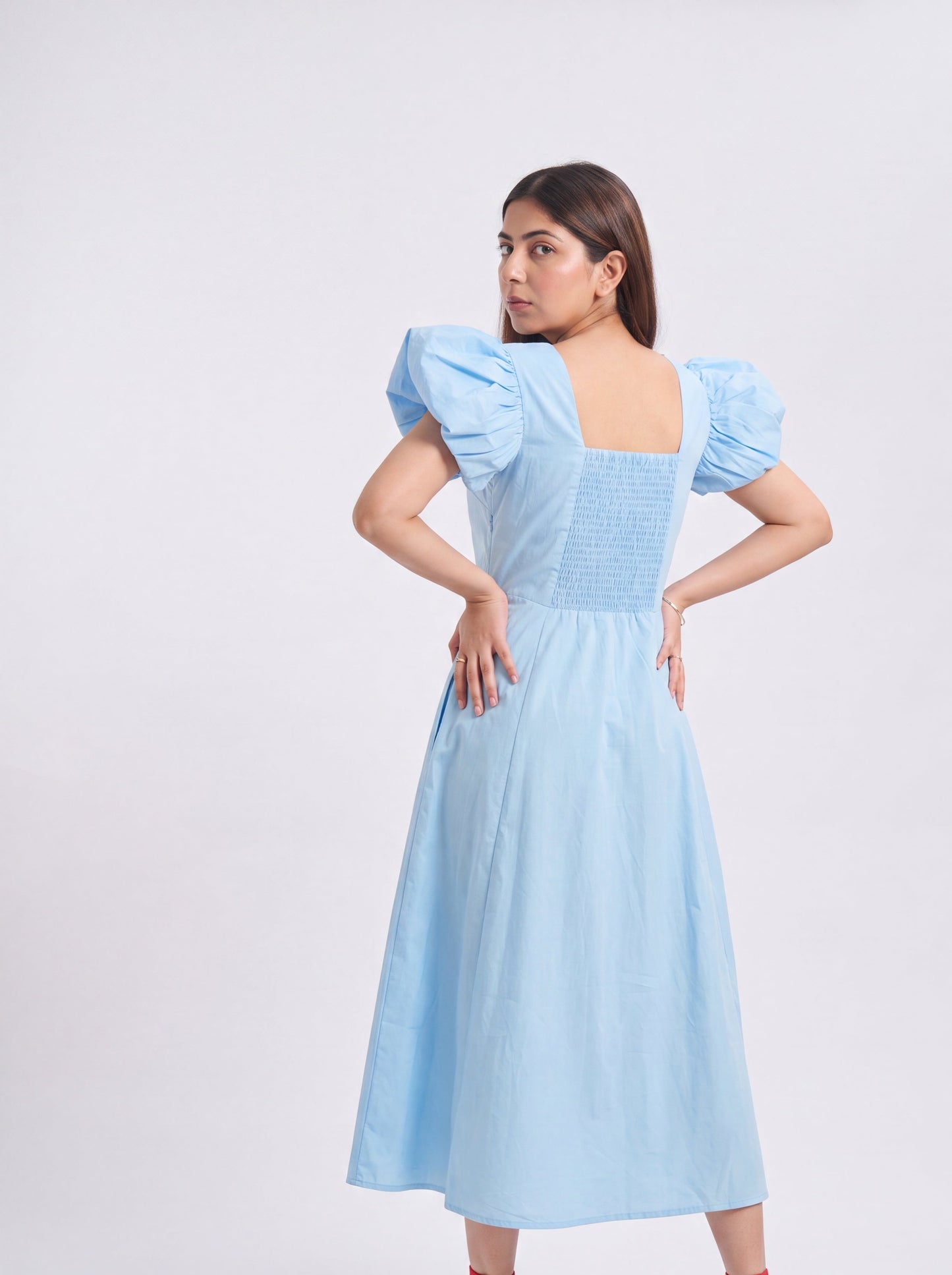 Woman wearing a light blue dress with puffed sleeves on a white background