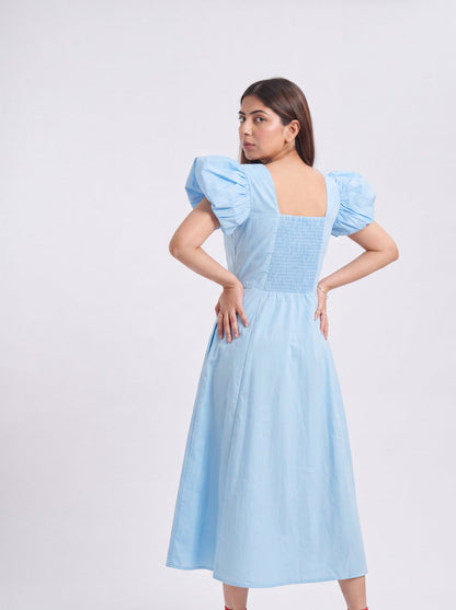 Woman wearing a light blue dress with puffed sleeves on a white background
