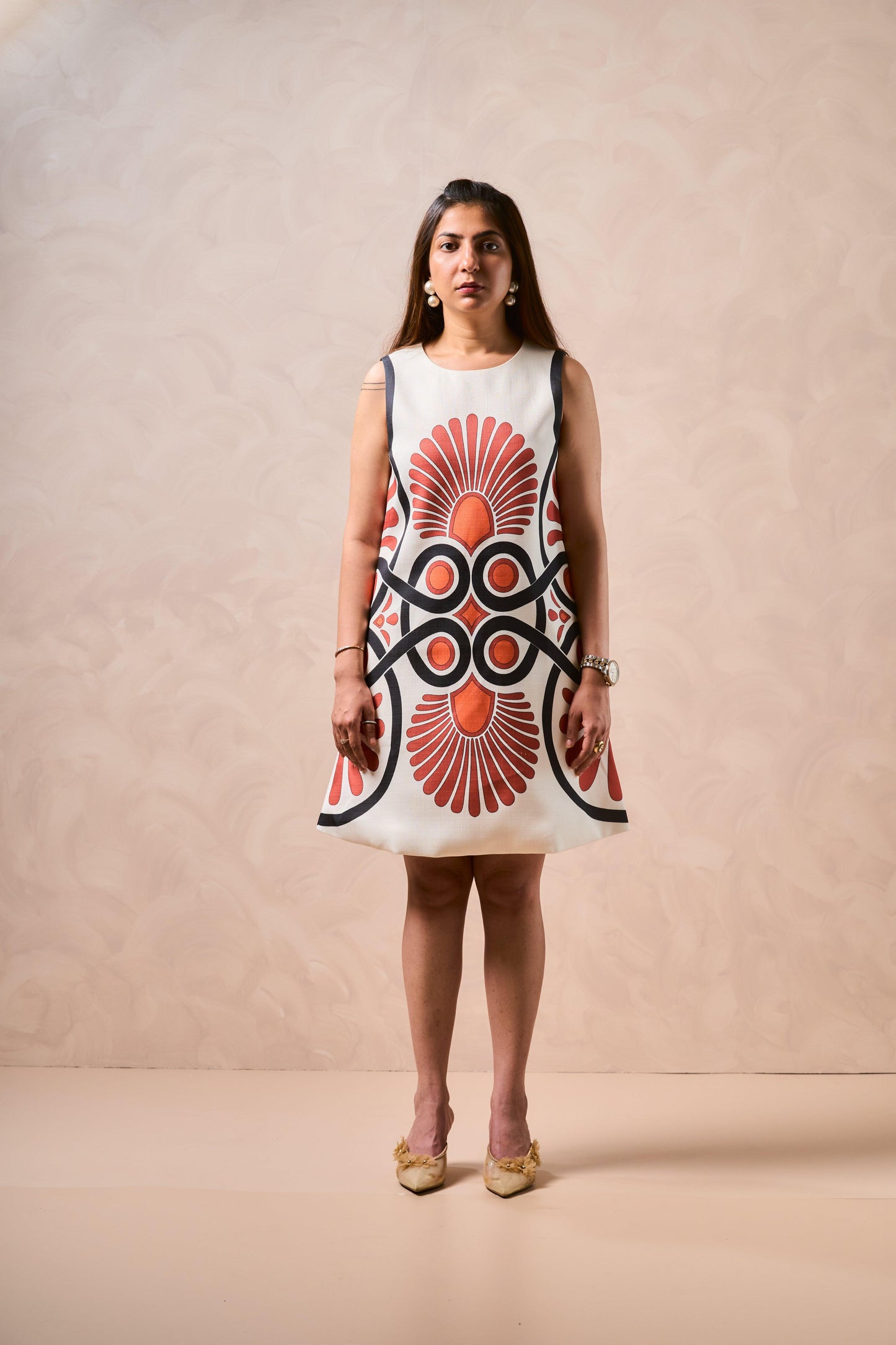 Woman wearing a sleeveless dress with a geometric pattern on a beige background