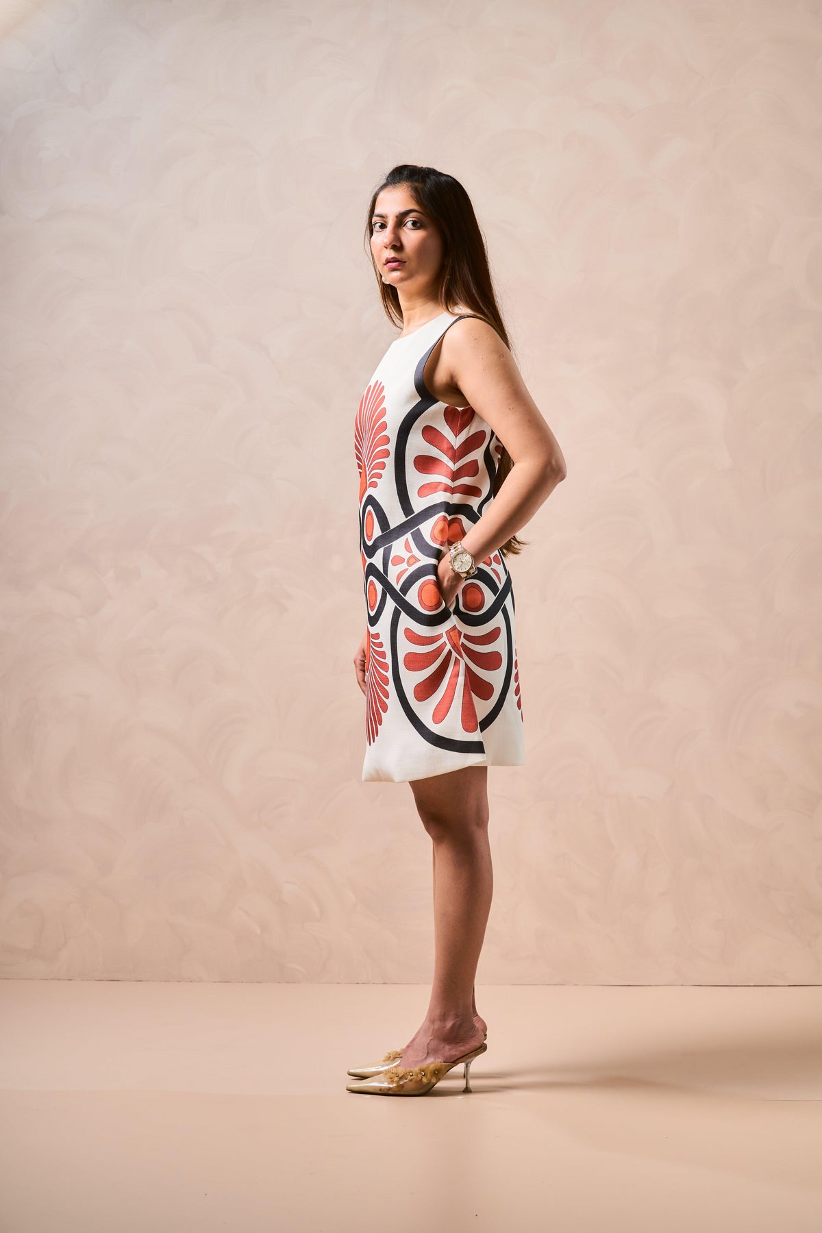 Woman wearing a white dress with red and black floral pattern on a beige background