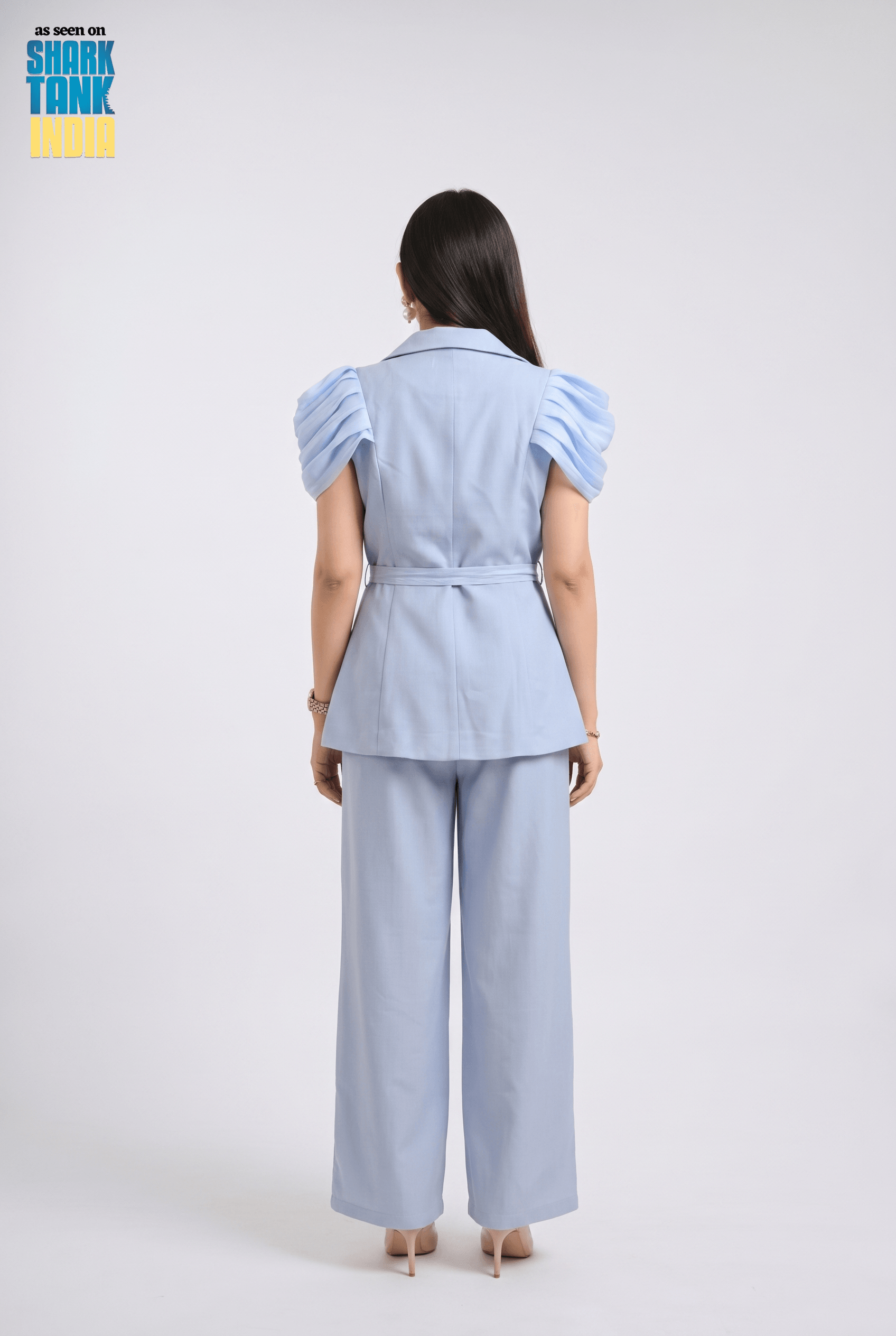Woman wearing a light blue outfit with puffed sleeves on a white background, featuring 'Shark Tank' branding.