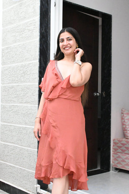 Woman in a coral dress standing in front of a door.