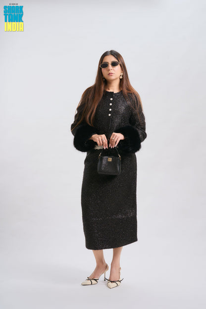 Woman wearing a black outfit with sunglasses and holding a handbag on a white background