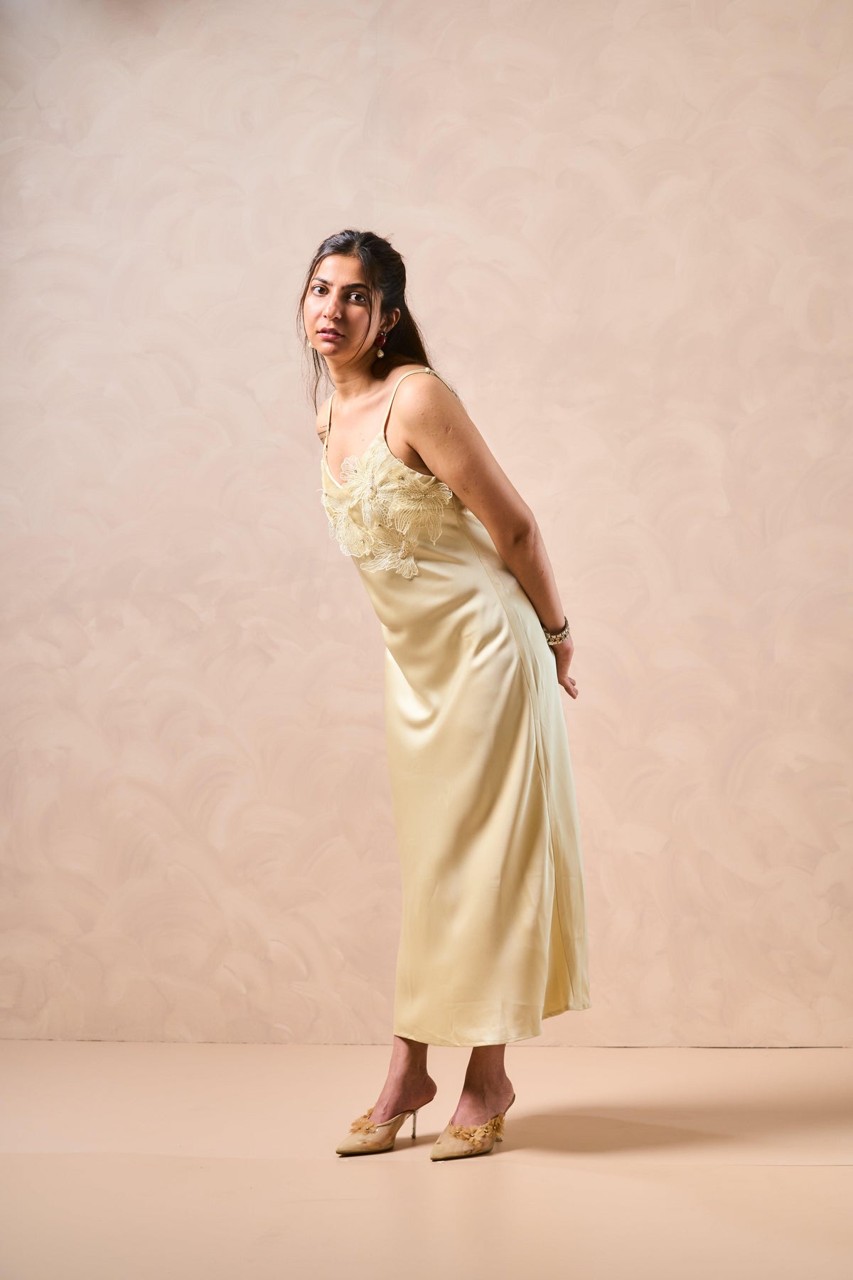 Woman wearing a light yellow dress against a beige background