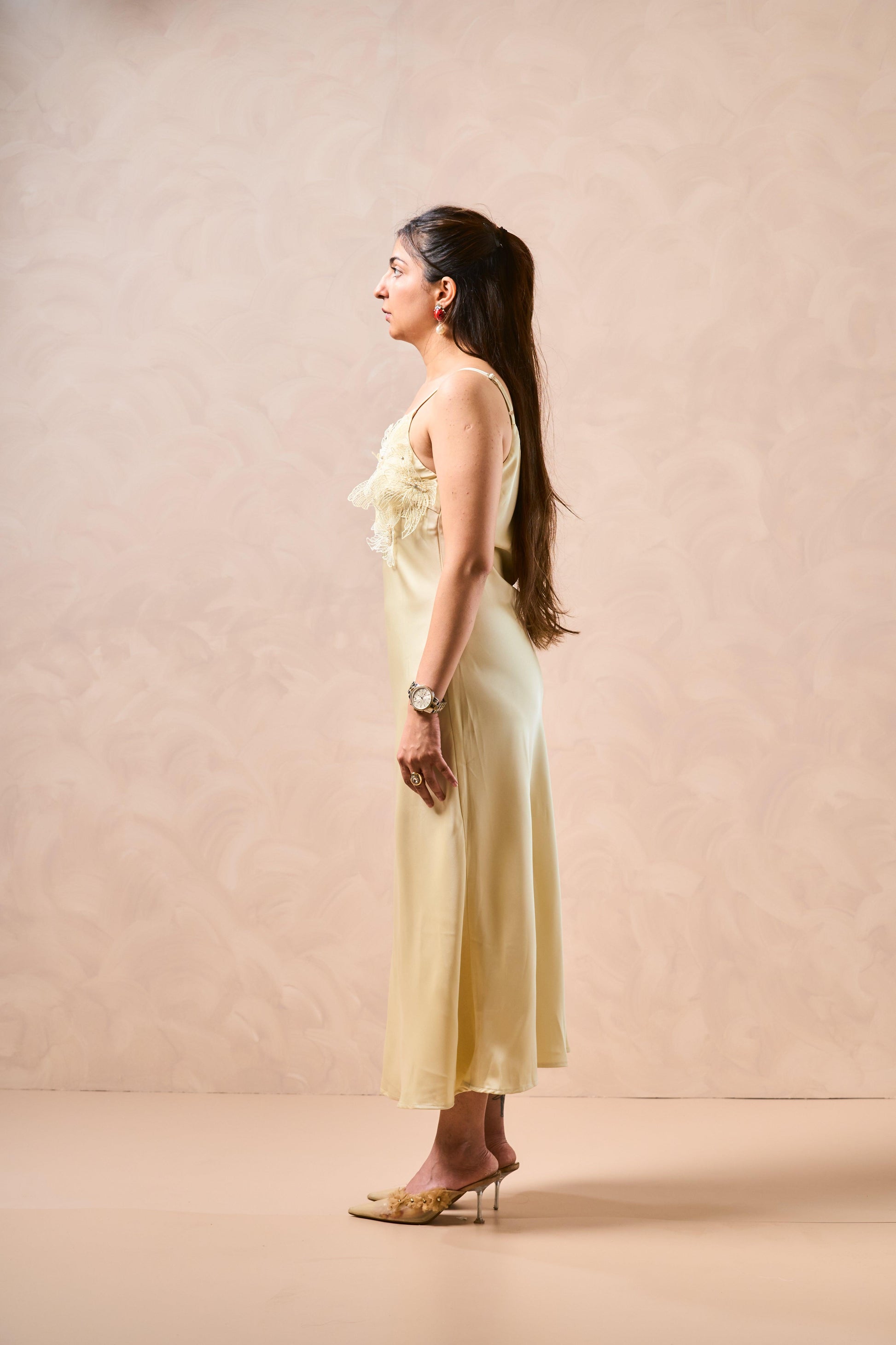 Woman in a light yellow dress standing against a beige background