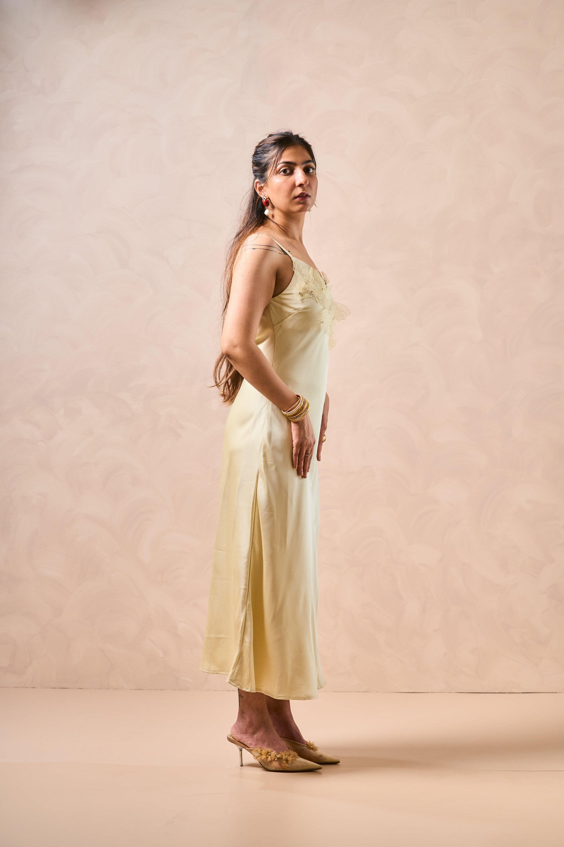 Woman wearing a light yellow dress against a beige background