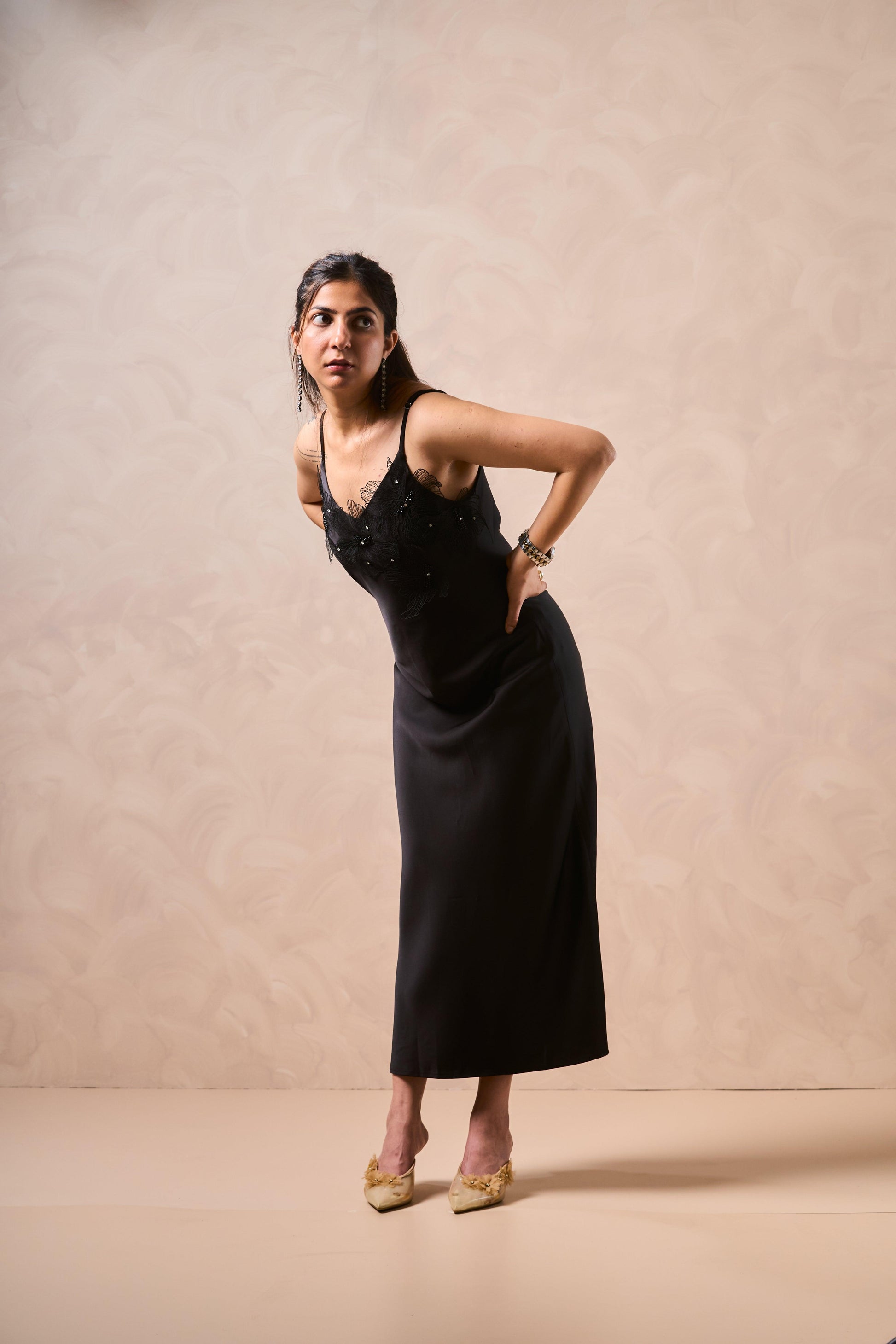 Woman wearing a black dress against a beige background