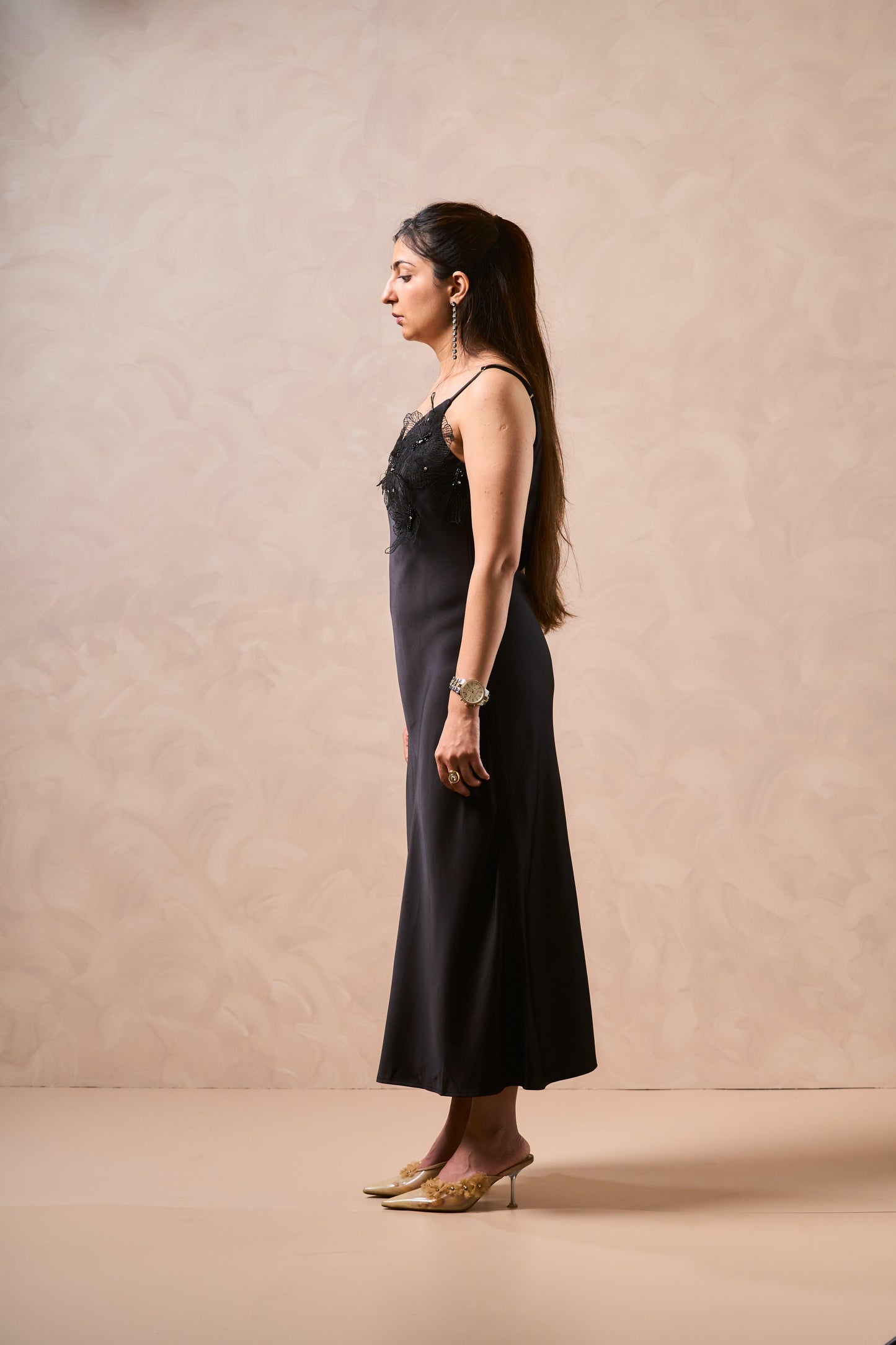 Woman wearing a black dress with floral details on a beige background