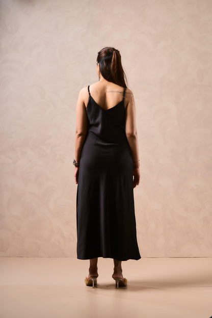 Woman wearing a black dress standing against a beige background