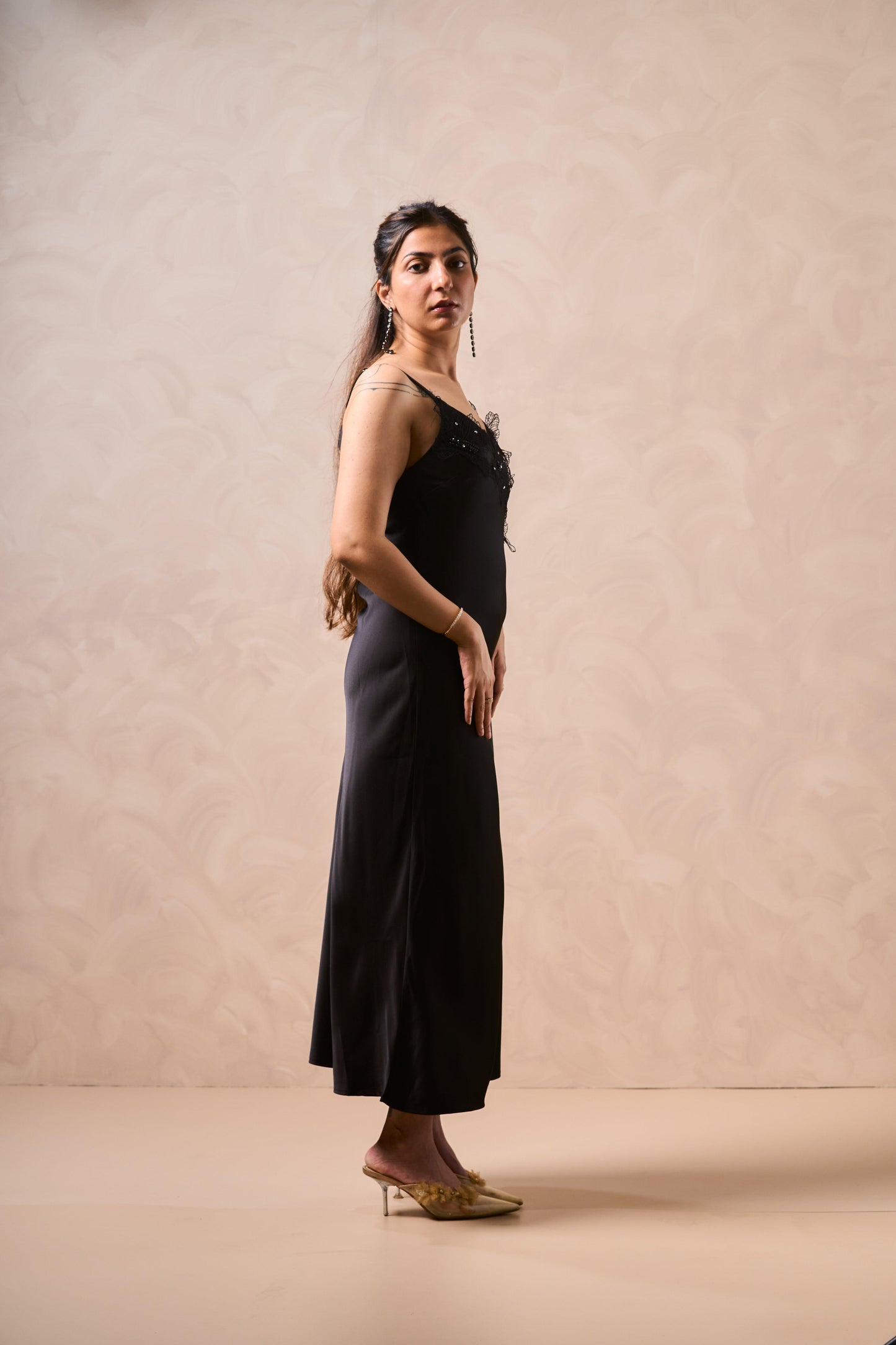 Woman wearing a black dress against a beige background