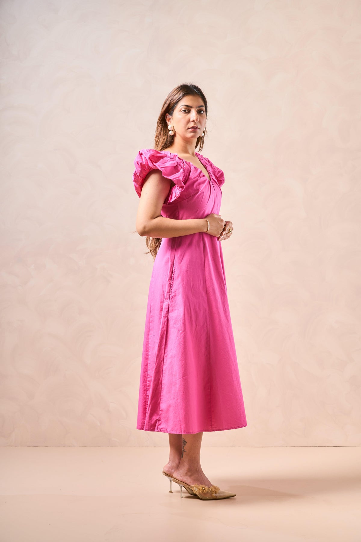Woman wearing a pink dress against a beige background
