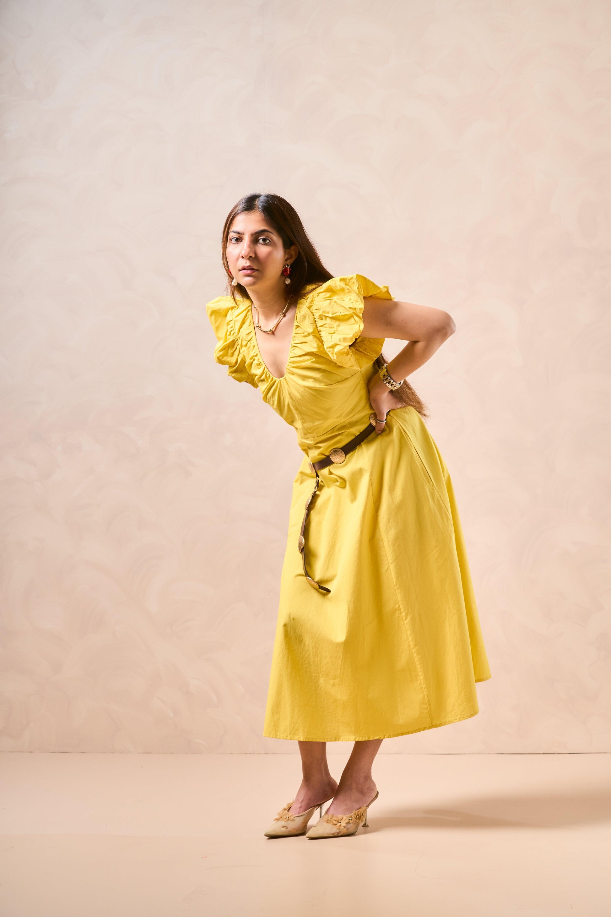 Woman wearing a yellow dress against a beige background