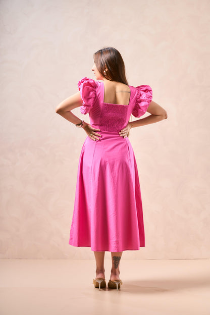 Woman wearing a pink dress with puffed sleeves against a beige background