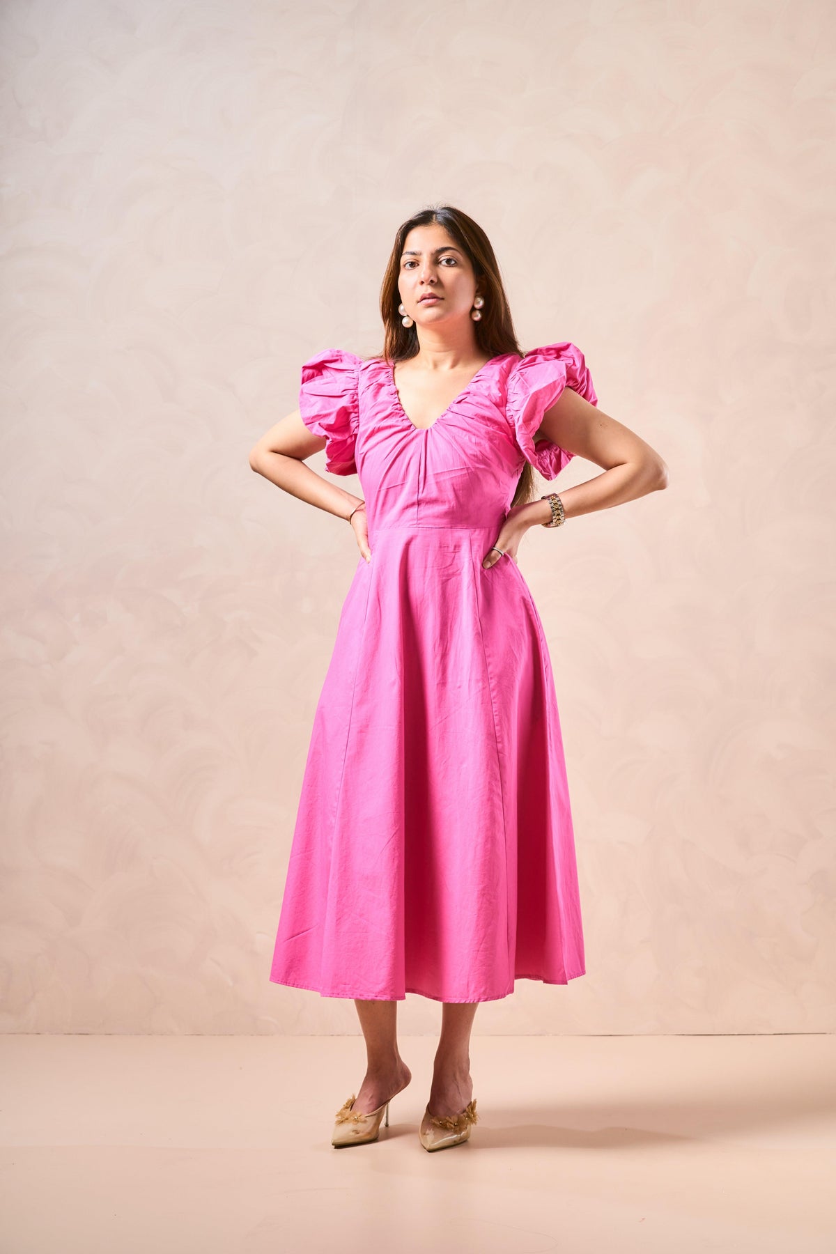 Woman wearing a pink dress against a beige background