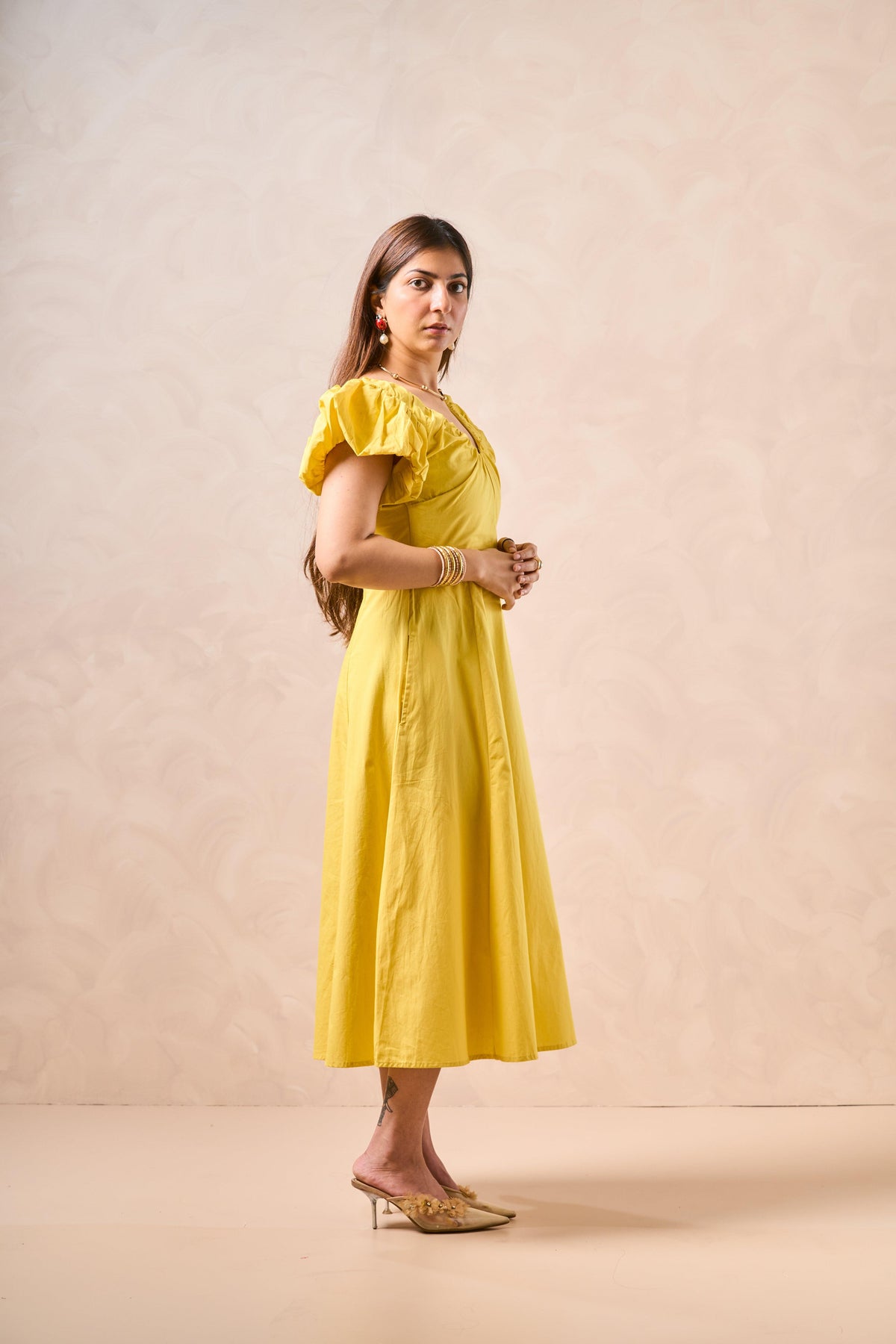 Woman wearing a yellow dress against a beige background