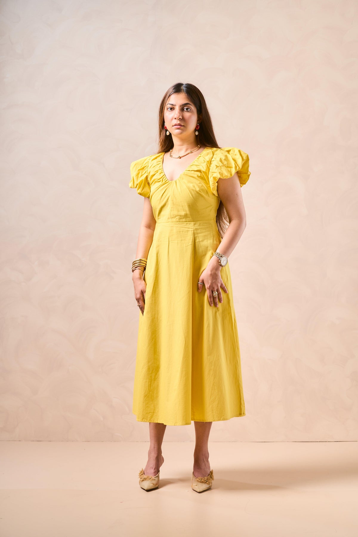 Woman wearing a yellow dress against a beige background