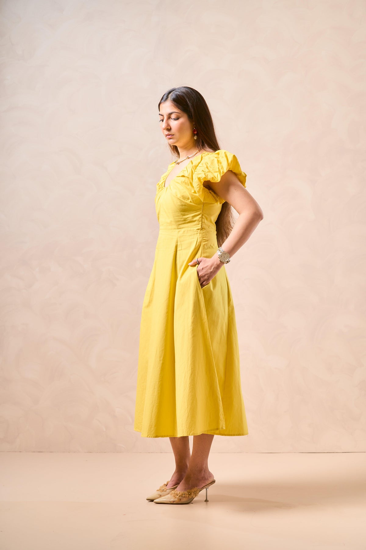 Woman wearing a yellow dress against a beige background