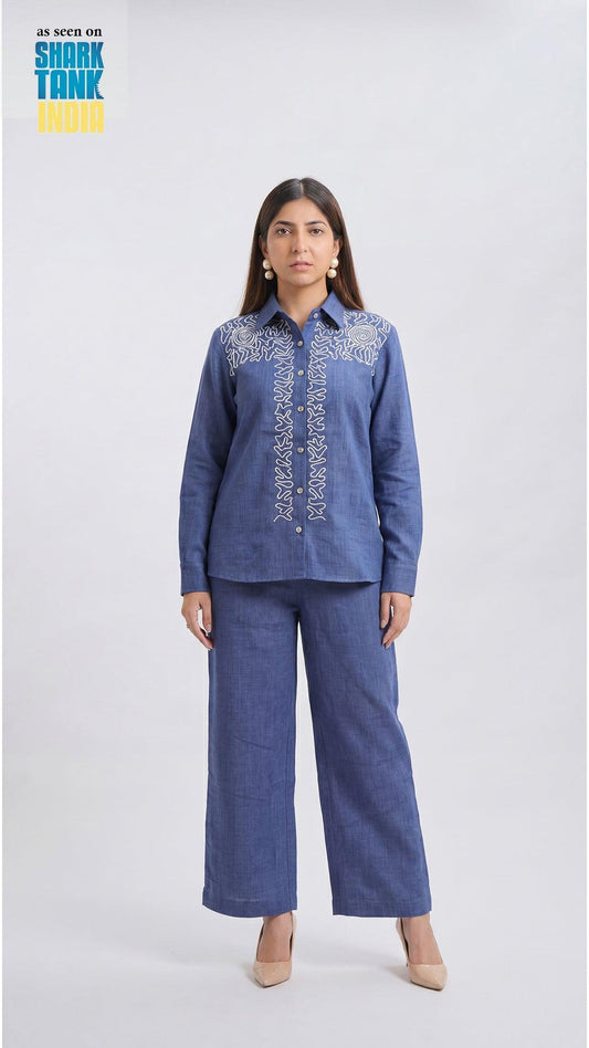 Woman wearing a blue embroidered outfit on a white background with 'Shark Tank' branding.