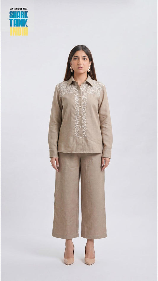 Woman wearing a beige outfit with embroidery on a white background