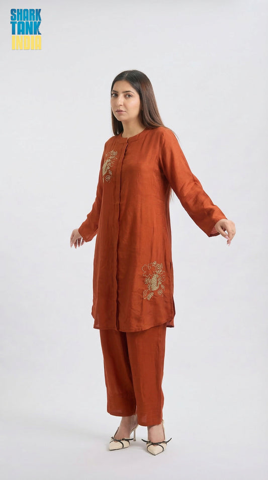 Woman wearing a rust-colored traditional outfit with embroidery on a white background