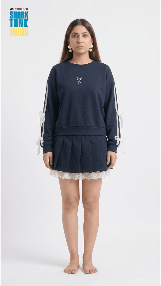 Woman wearing a navy blue sweatshirt with white stripes and a matching skirt on a white background.