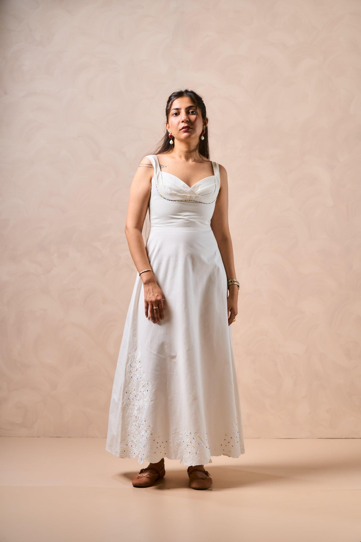 Woman wearing a white dress against a beige background