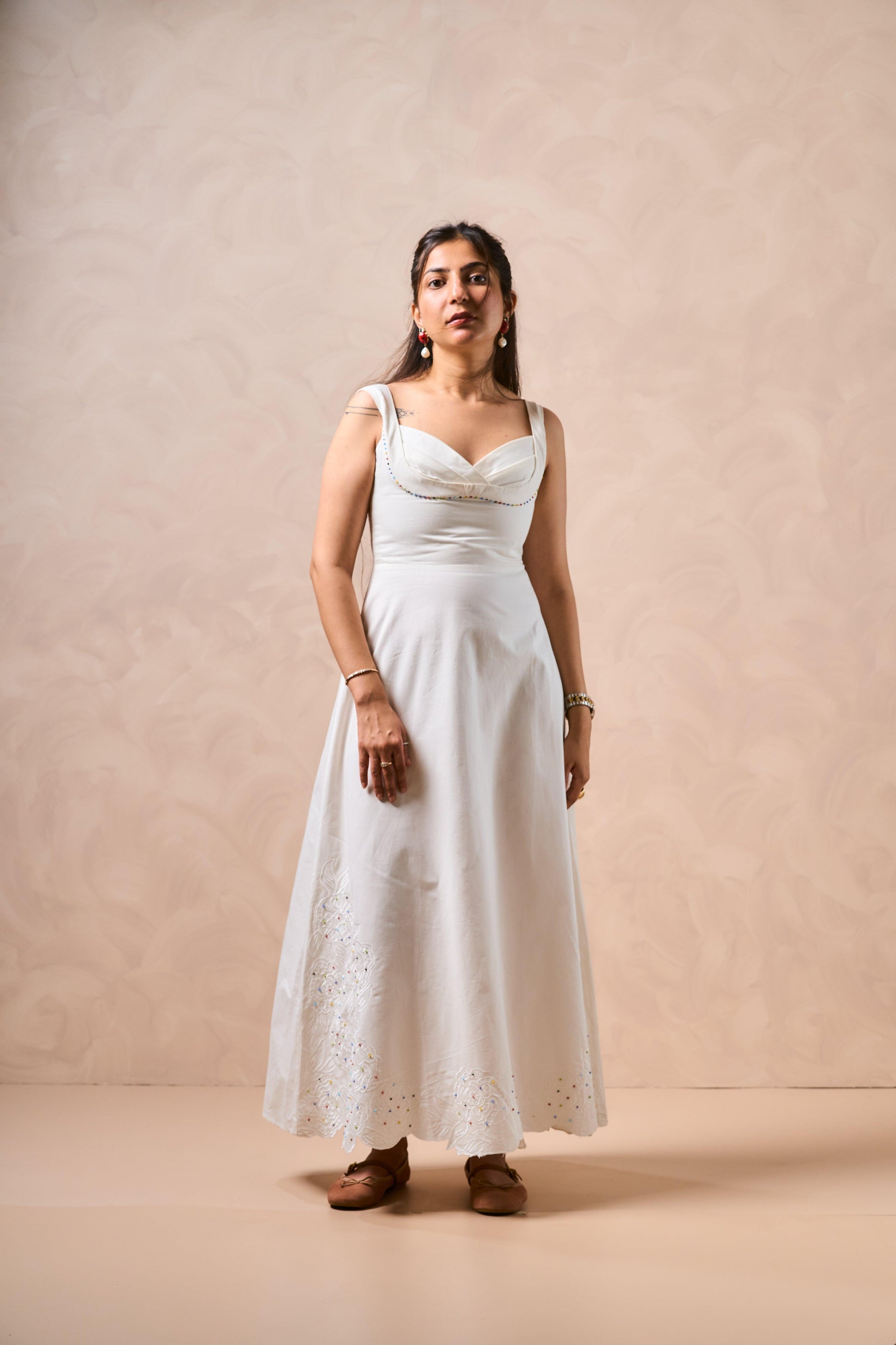 Woman wearing a white dress against a beige background