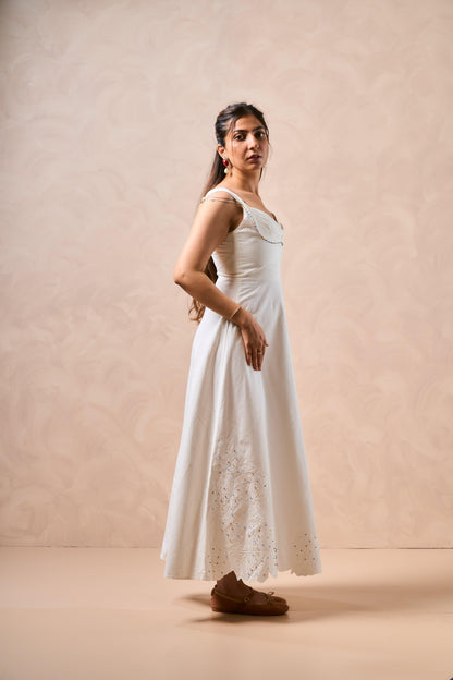 Woman wearing a white dress standing against a beige background