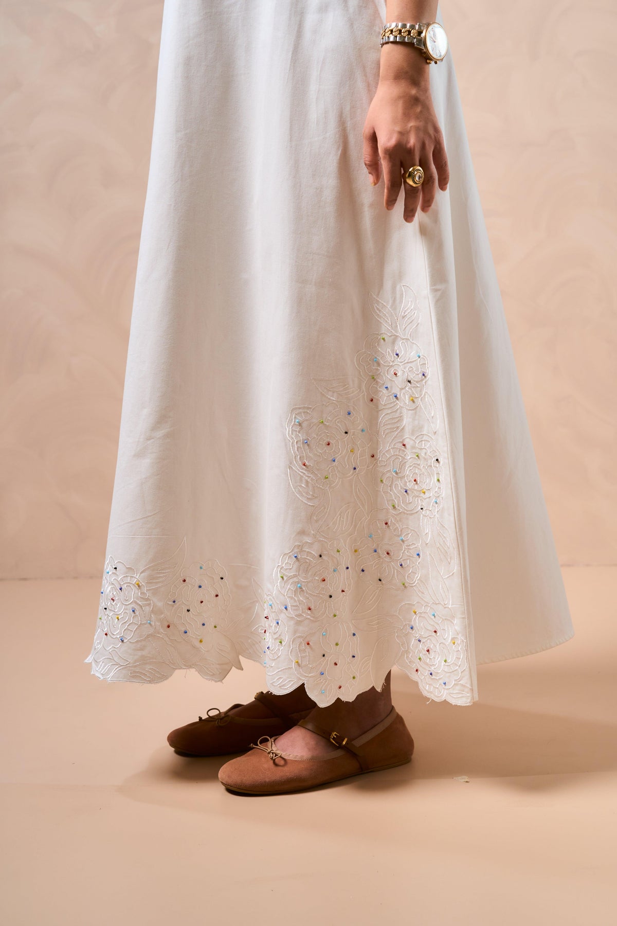 White lace dress with brown shoes on a beige background